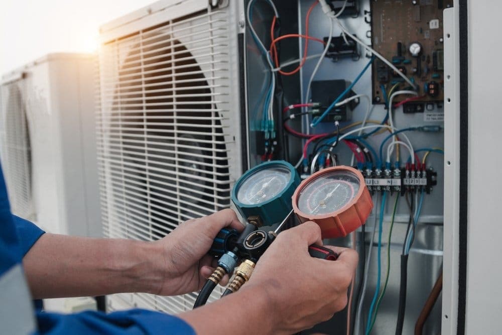 Técnico leyendo los manómetros de presión de refrigerante de un aire acondicionado
